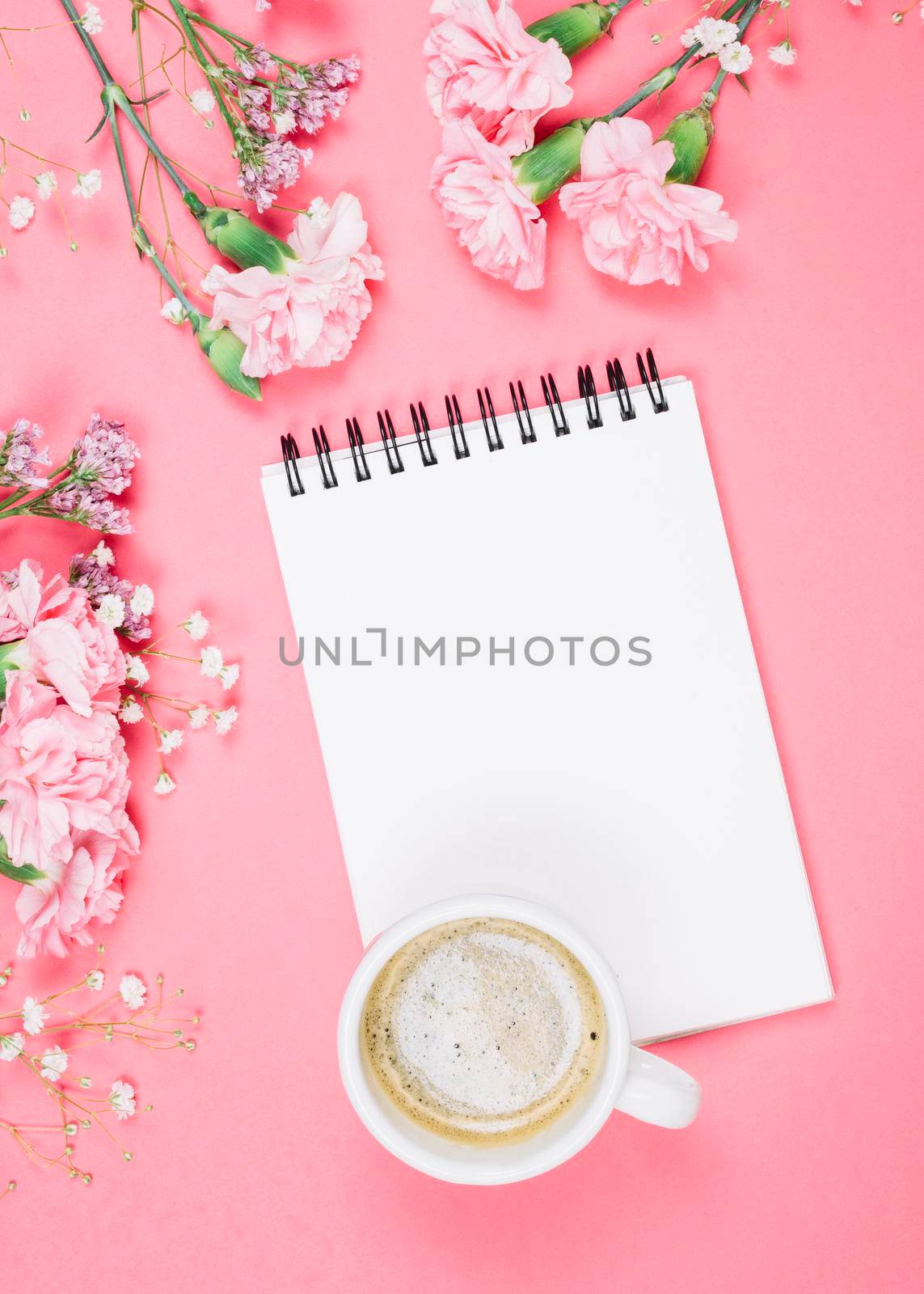 overhead view coffee cup blank notepad with carnations gypsophila limonium flowers pink background