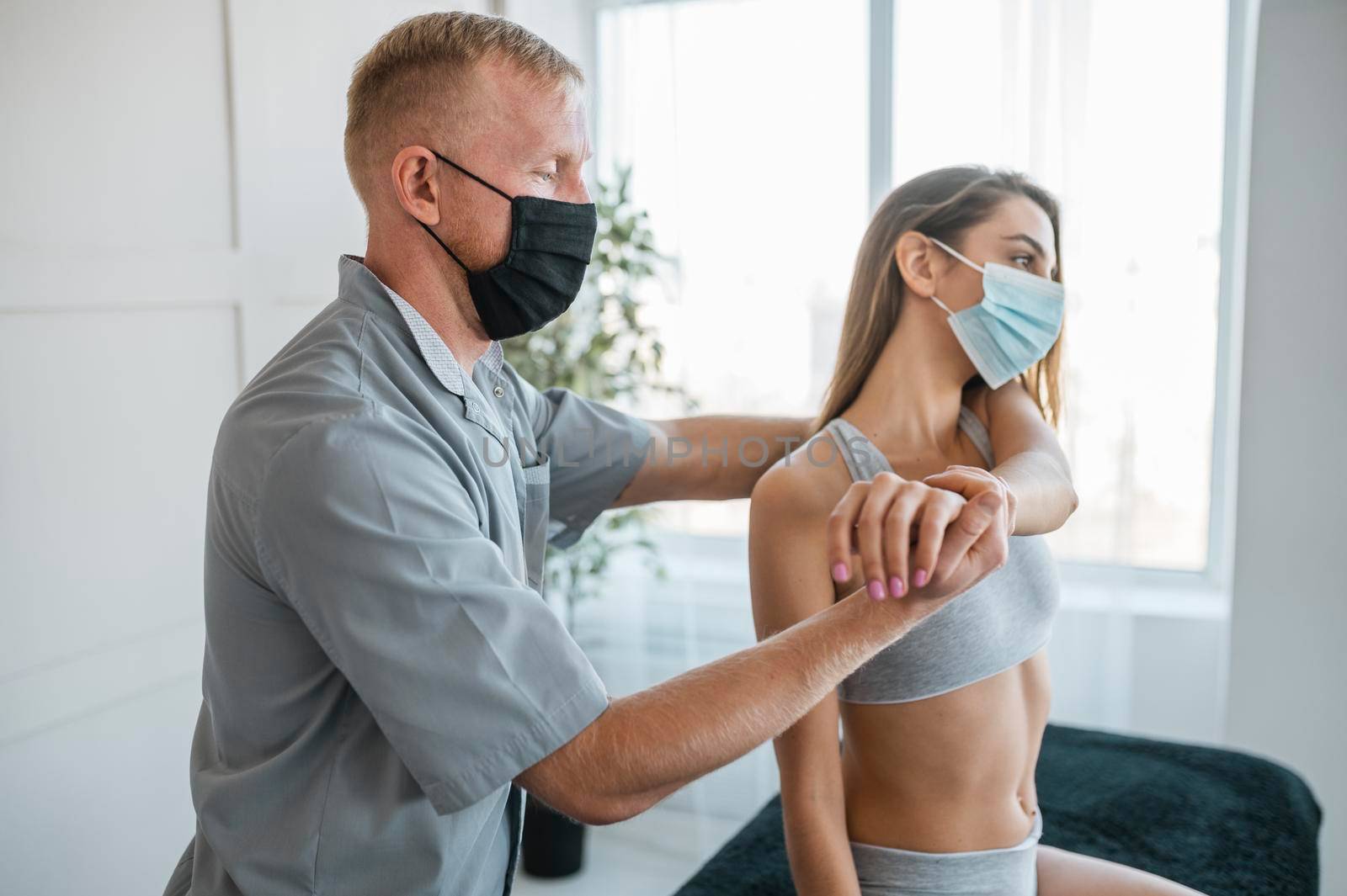 physiotherapist wearing medical mask during therapy session with female patient by Zahard