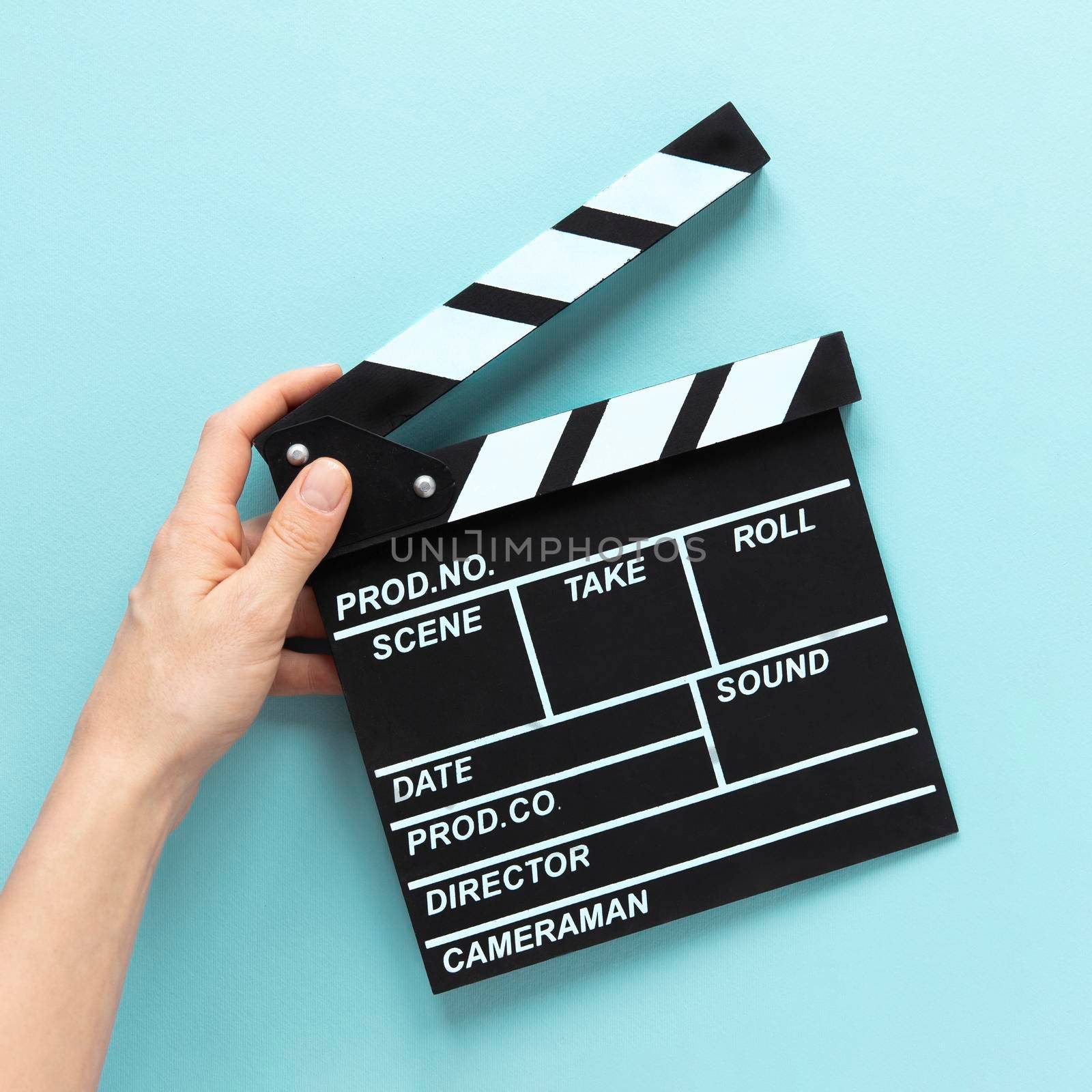 person holding movie clapper blue background