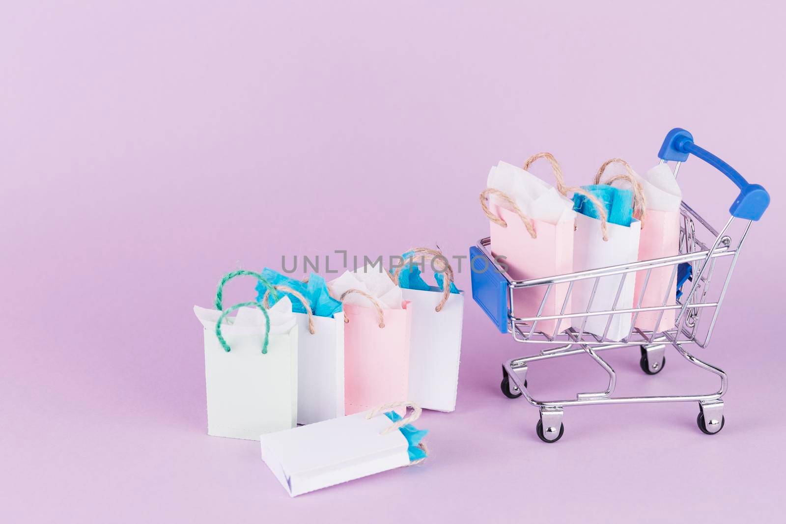 many colorful paper shopping bags cart pink background by Zahard