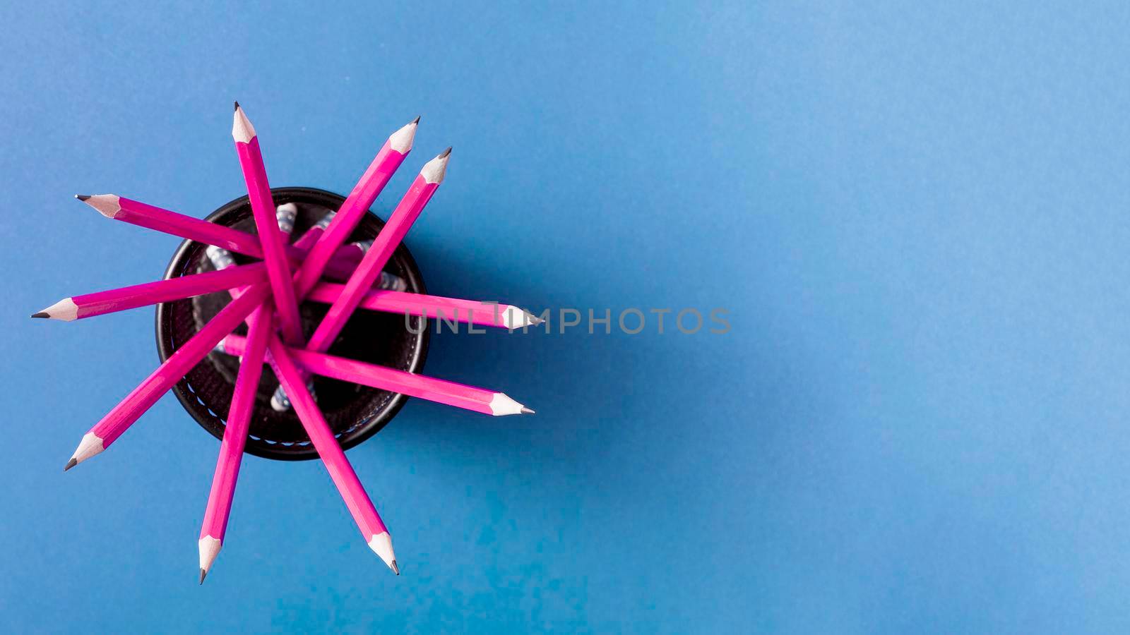 pink pencils holder against blue background