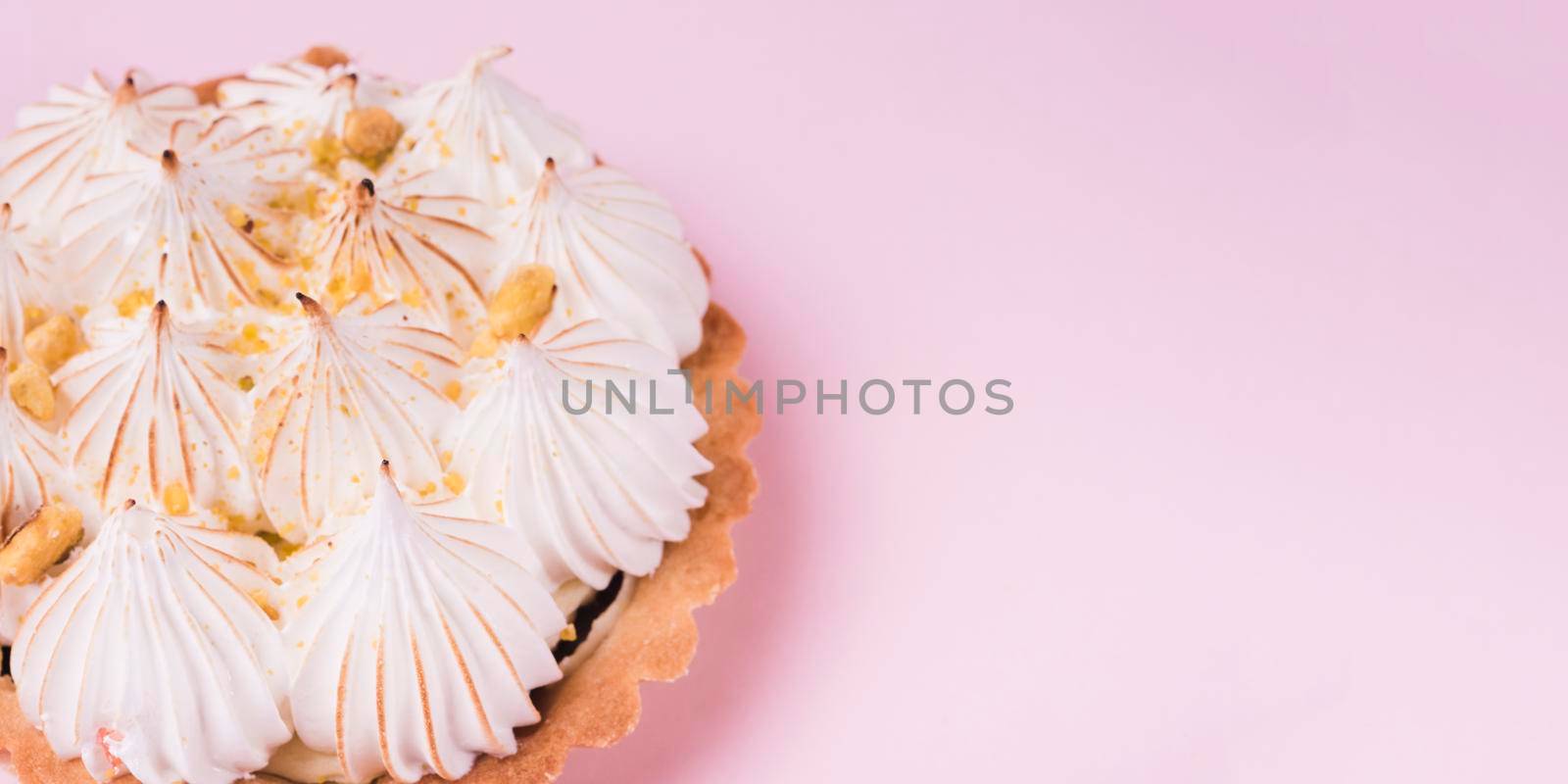 close up lemon tart with italian meringue pink backdrop