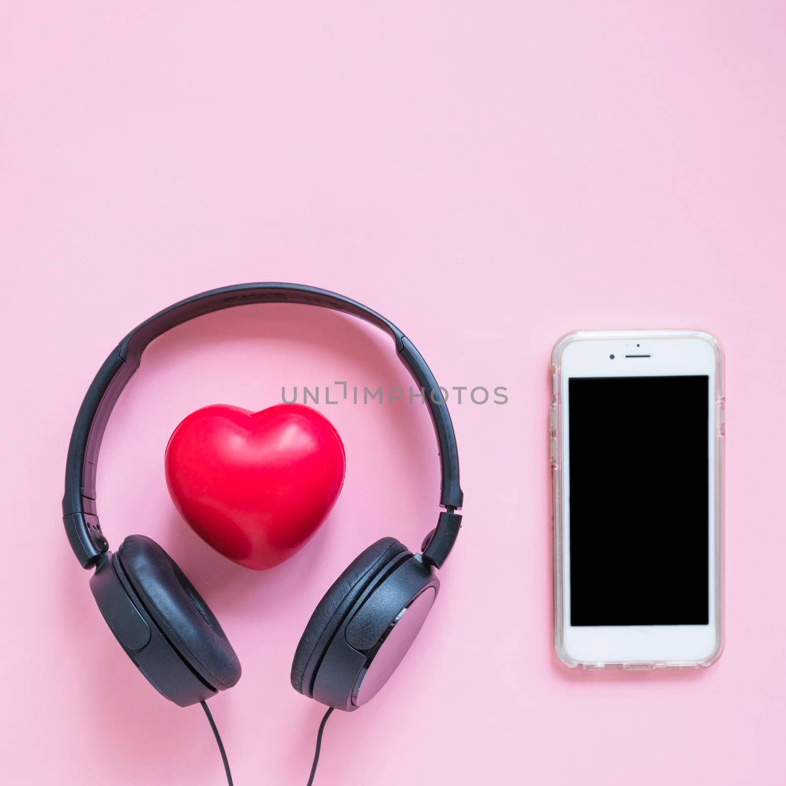 headphone around red heart shape smartphone against pink backdrop by Zahard