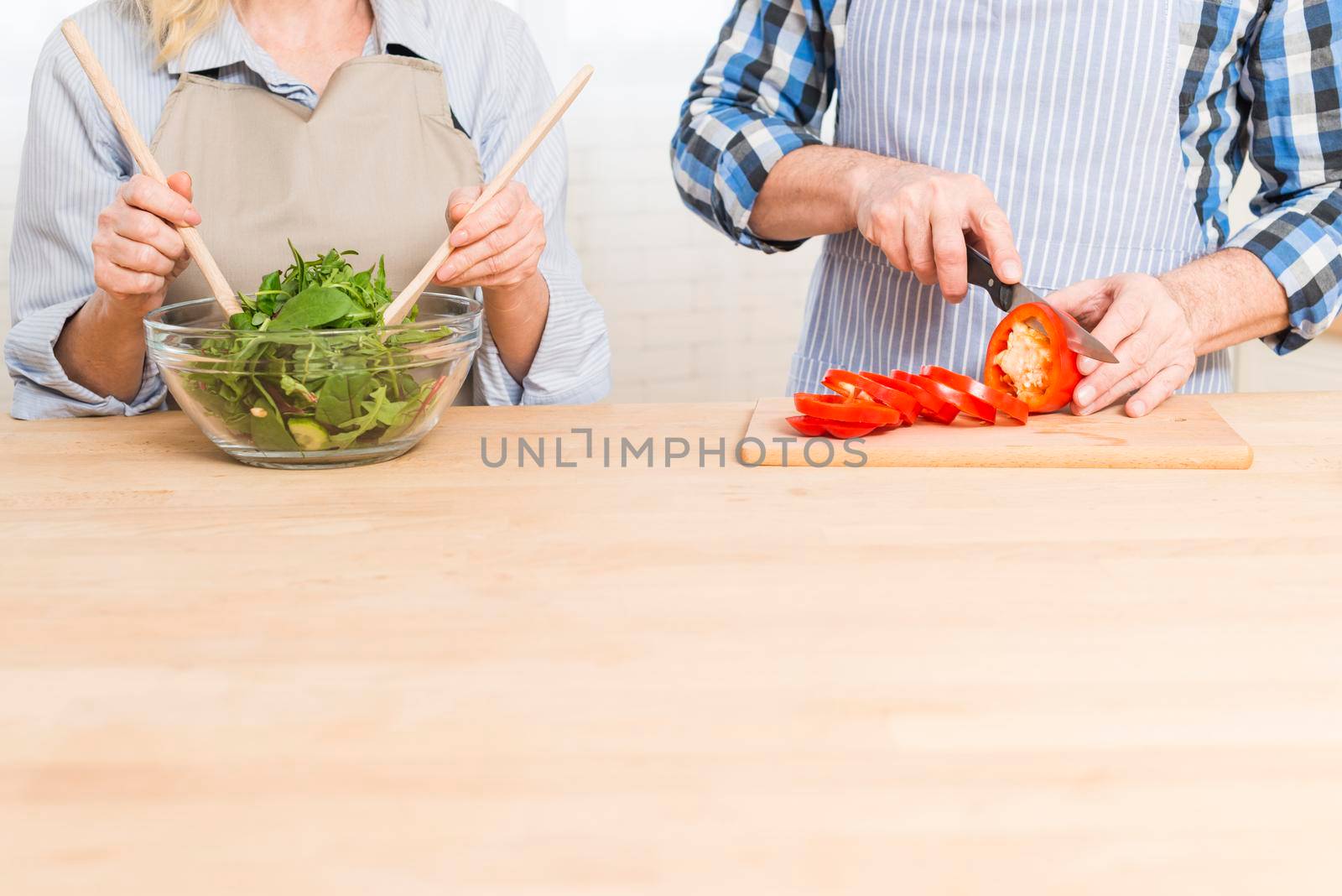 close up woman preparing salad her husband cutting bell pepper wooden table by Zahard