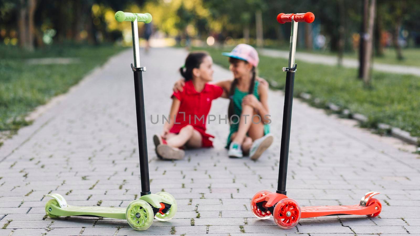push scooters front girls sitting walkway park