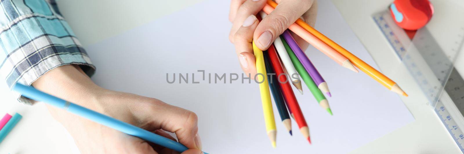 Woman designer drawing with multicolored pencils on paper closeup. Fine art lessons concept