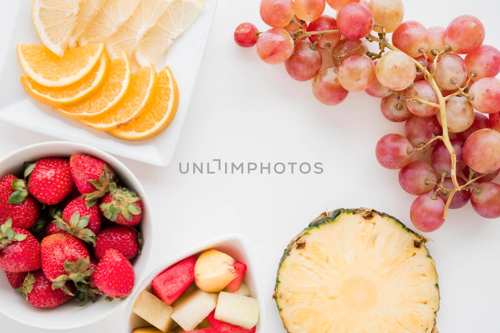 slices citrus fruit strawberry pineapple watermelon grapes white backdrop