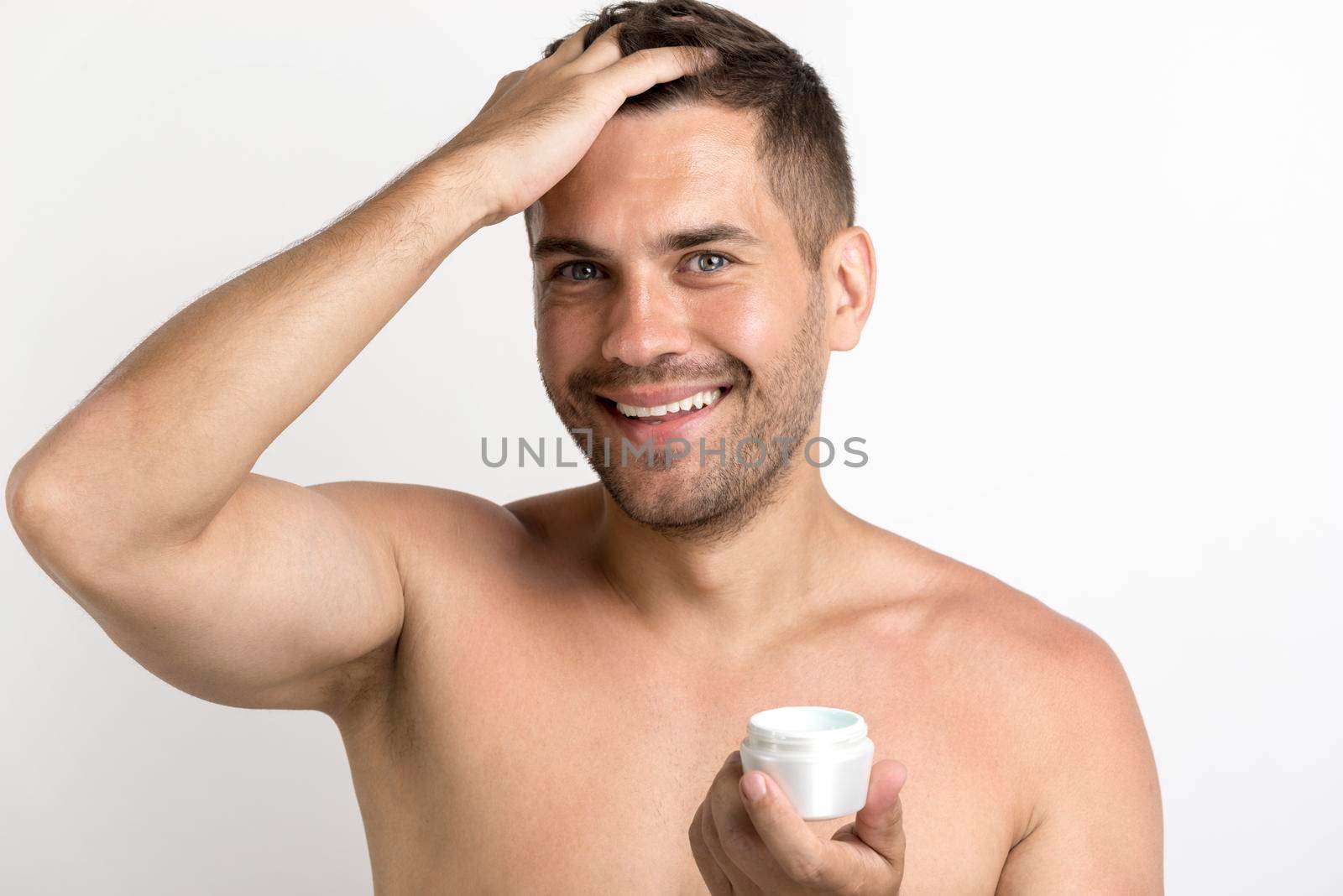 portrait happy man applying hair wax standing against white background