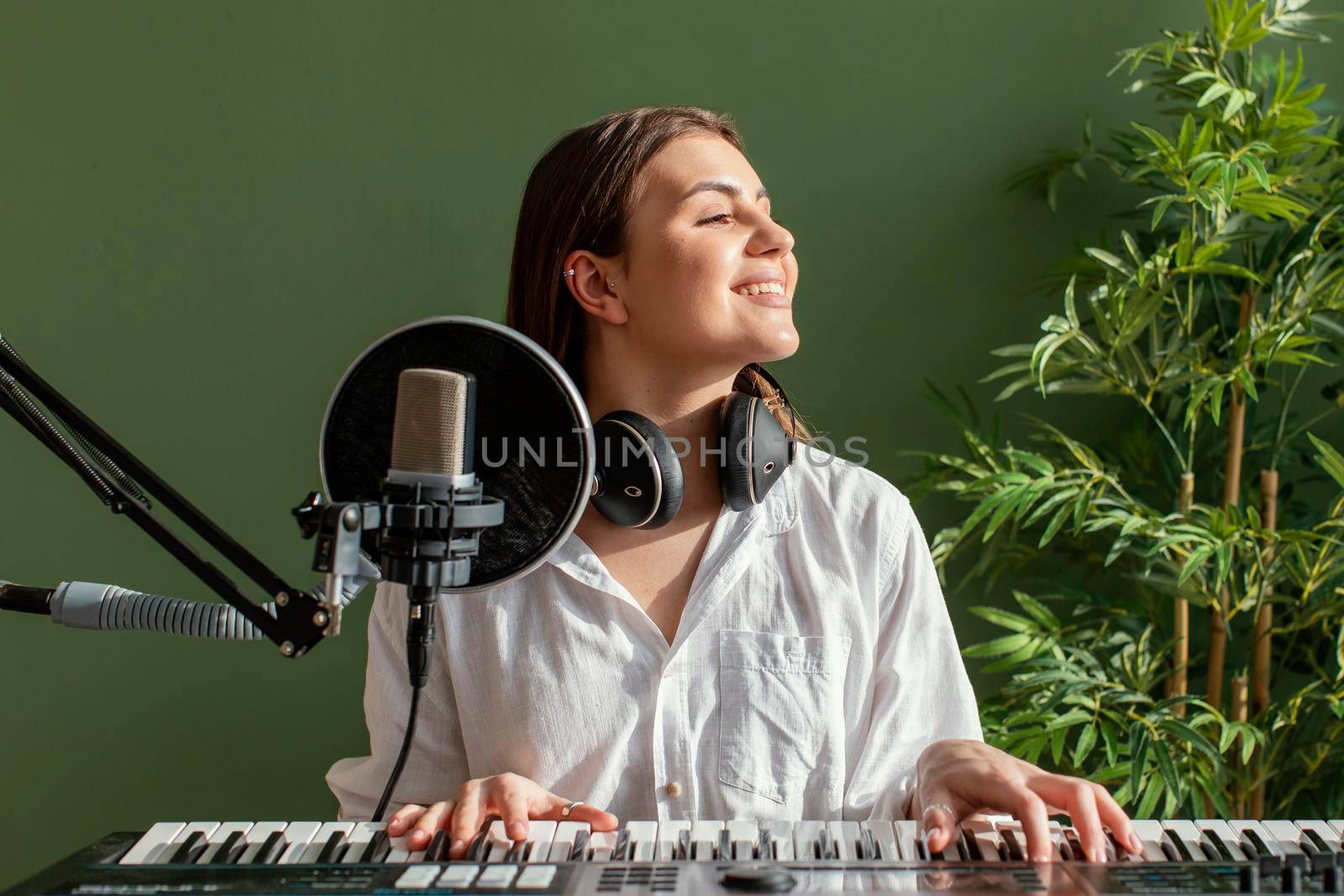 front view smiley female musician playing piano keyboard indoors