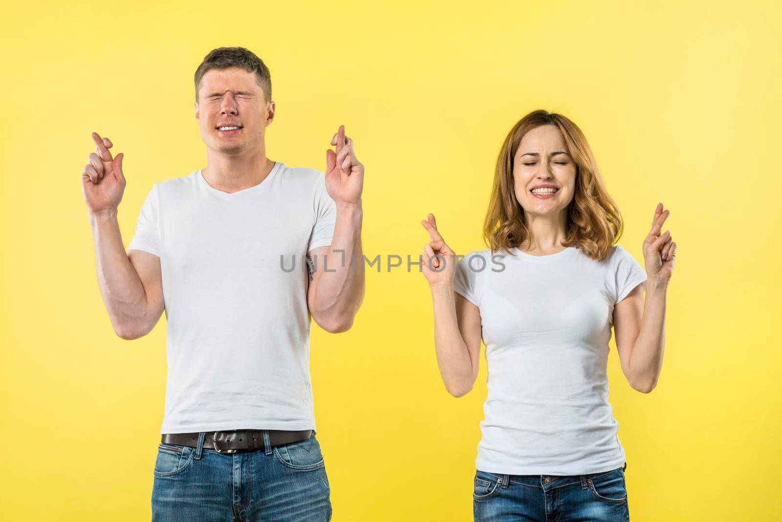 smiling young couple crosses fingers anticipation something pleasant