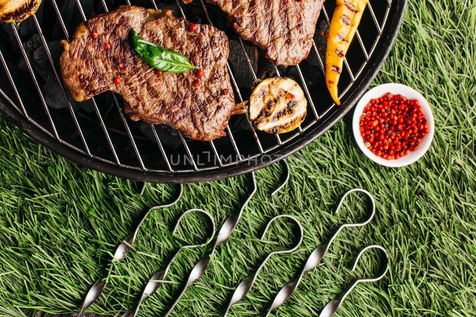 grilled steak vegetable with metallic skewer barbecue grill green grass background by Zahard