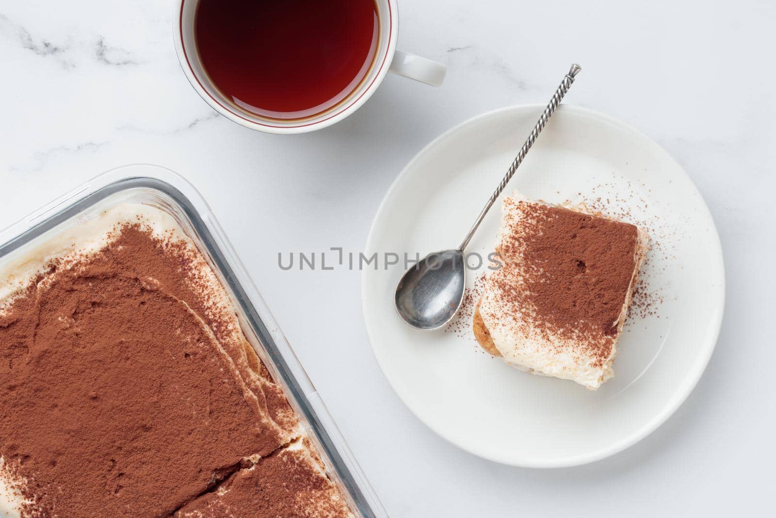 Piece of Homemade Tiramisu cake dessert and coffee on a white marble background