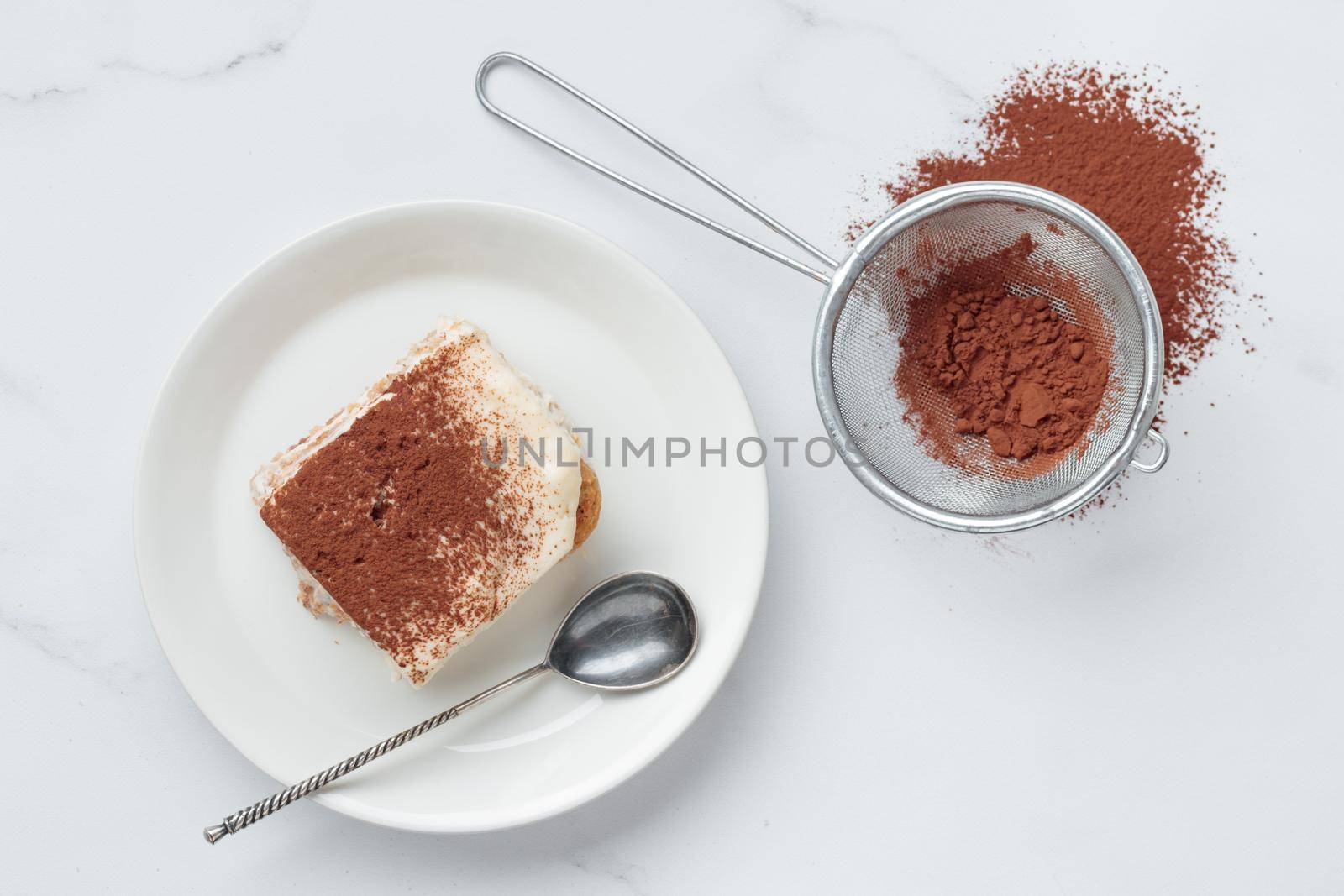 Piece of Homemade Tiramisu cake dessert and cocoa on a white marble background