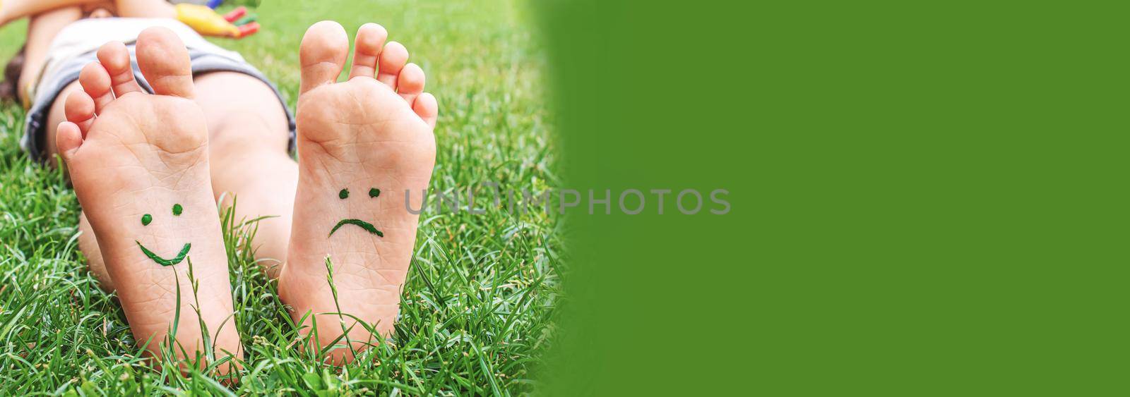 Baby feet with paint pattern are smiling and sad on the green grass. Selective focus. nature.