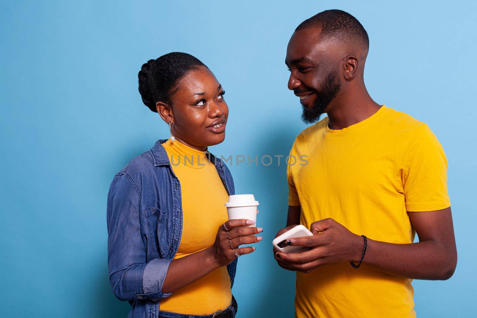 Modern couple with smartphone enjoying laugh and looking at each other by DCStudio