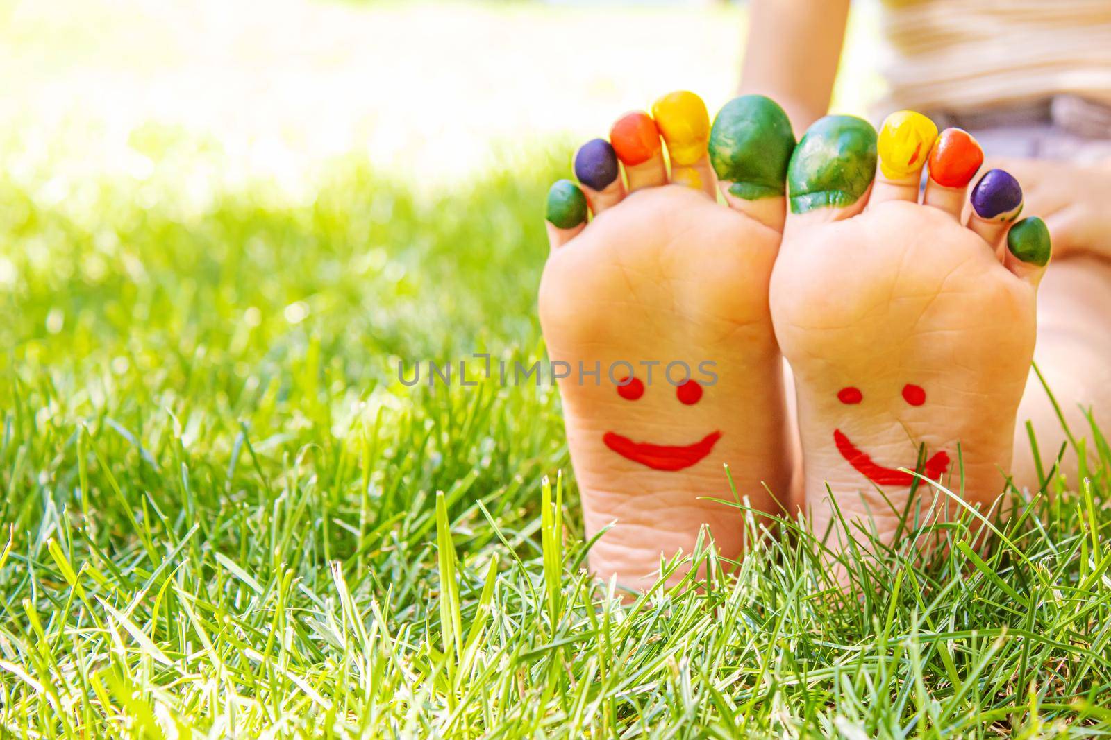 Children's feet with a pattern of paints smile on the green grass. Selective focus. nature.
