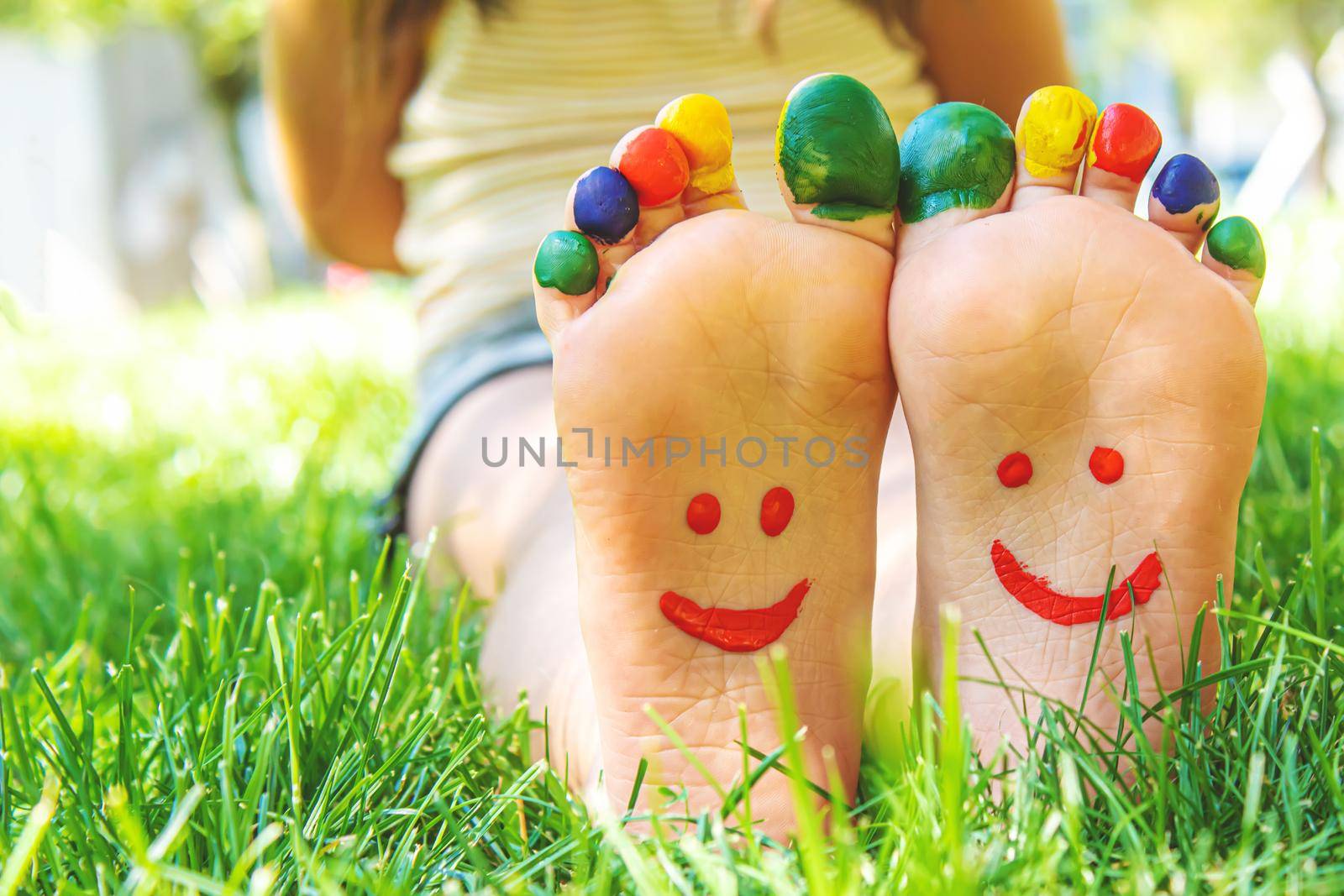 Children's feet with a pattern of paints smile on the green grass. Selective focus. nature.
