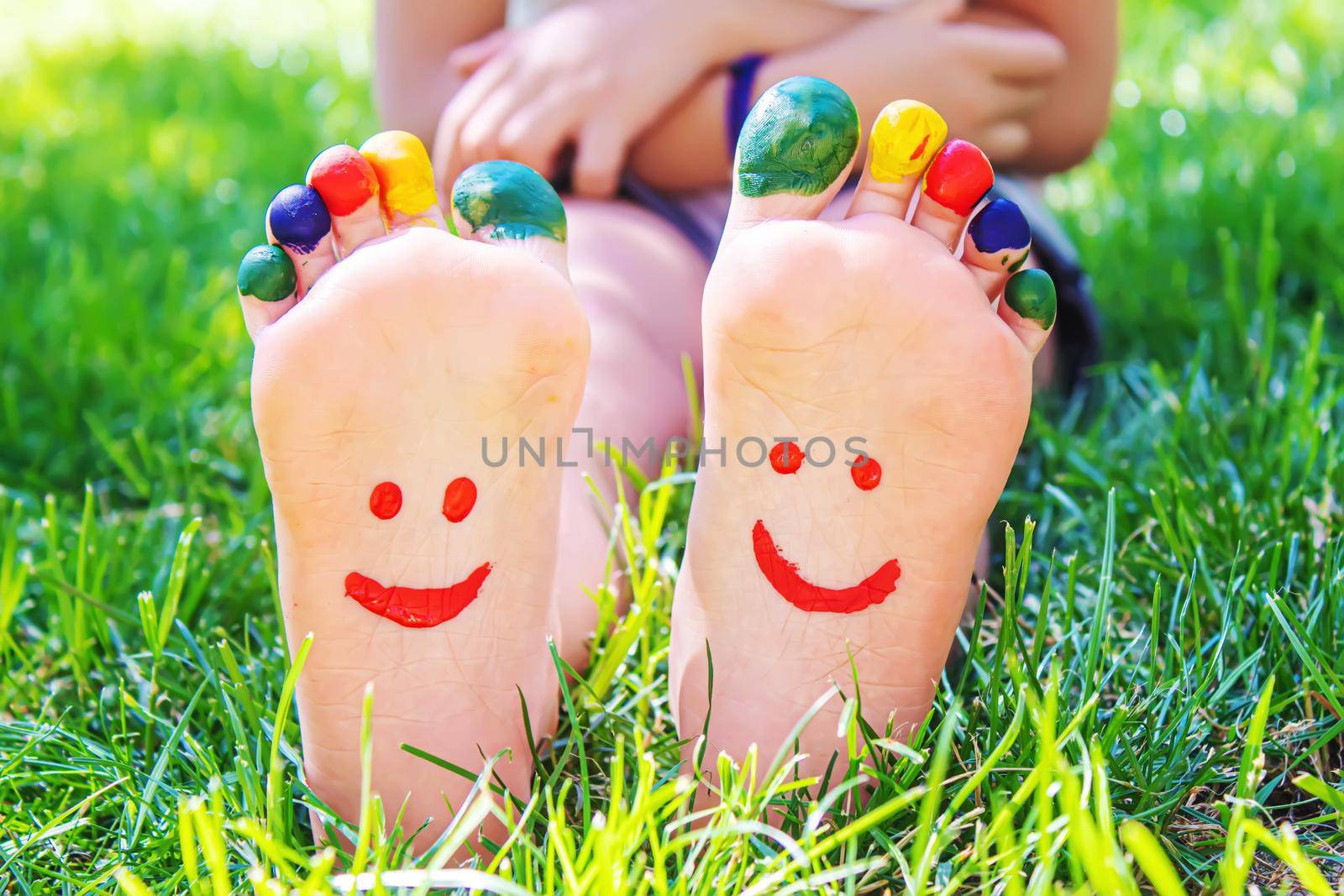 Children's feet with a pattern of paints smile on the green grass. Selective focus. nature.