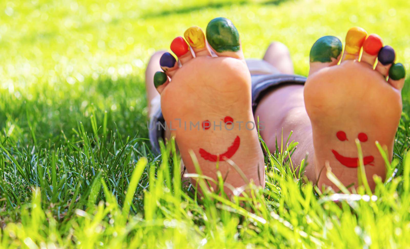 Children's feet with a pattern of paints smile on the green grass. Selective focus. nature.
