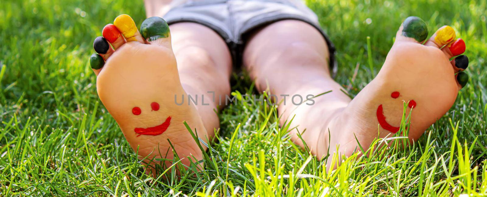 Children's feet with a pattern of paints smile on the green grass. Selective focus. by mila1784