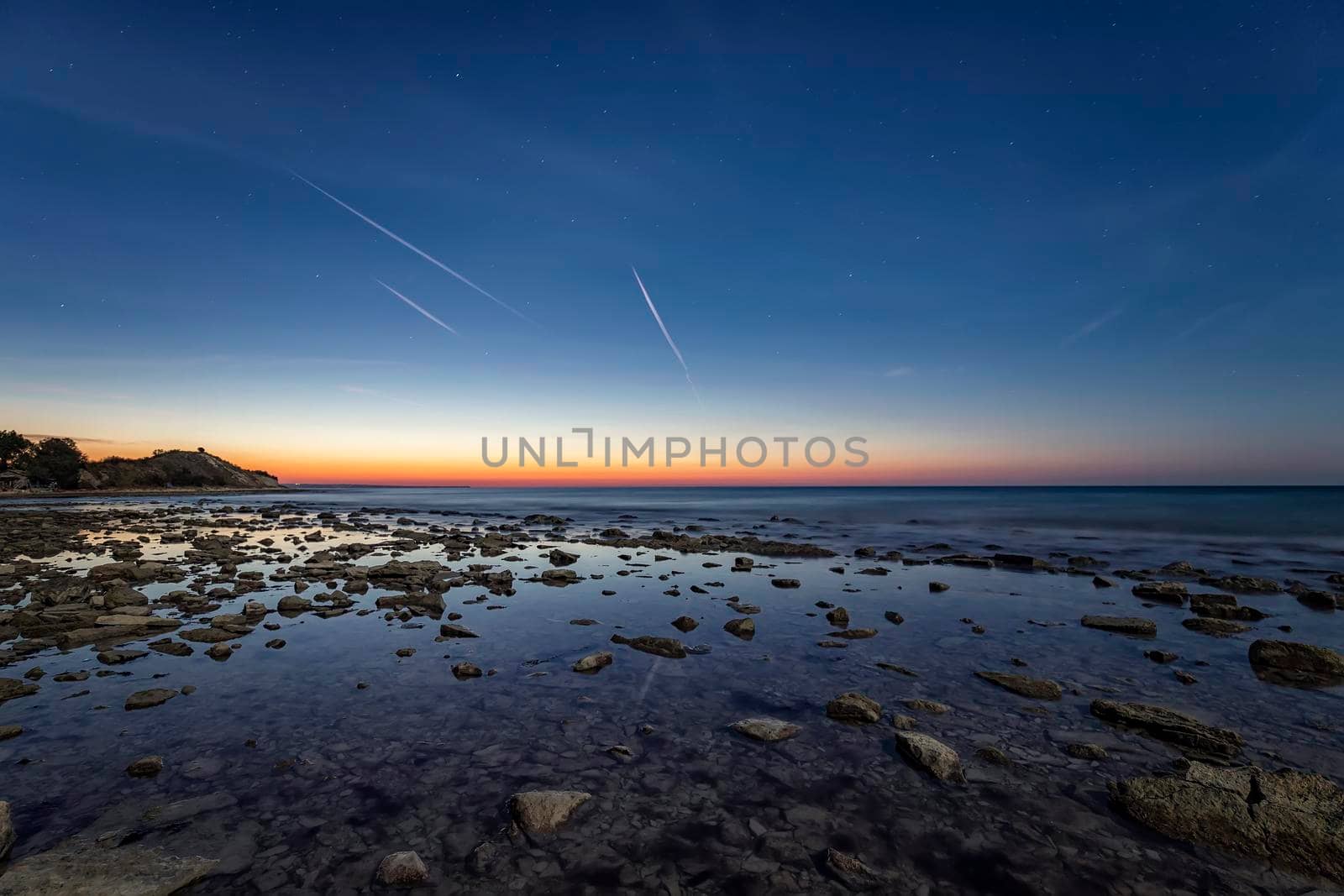 an amazing tranquil scene of a rocky shore before sunrise. Blue hour