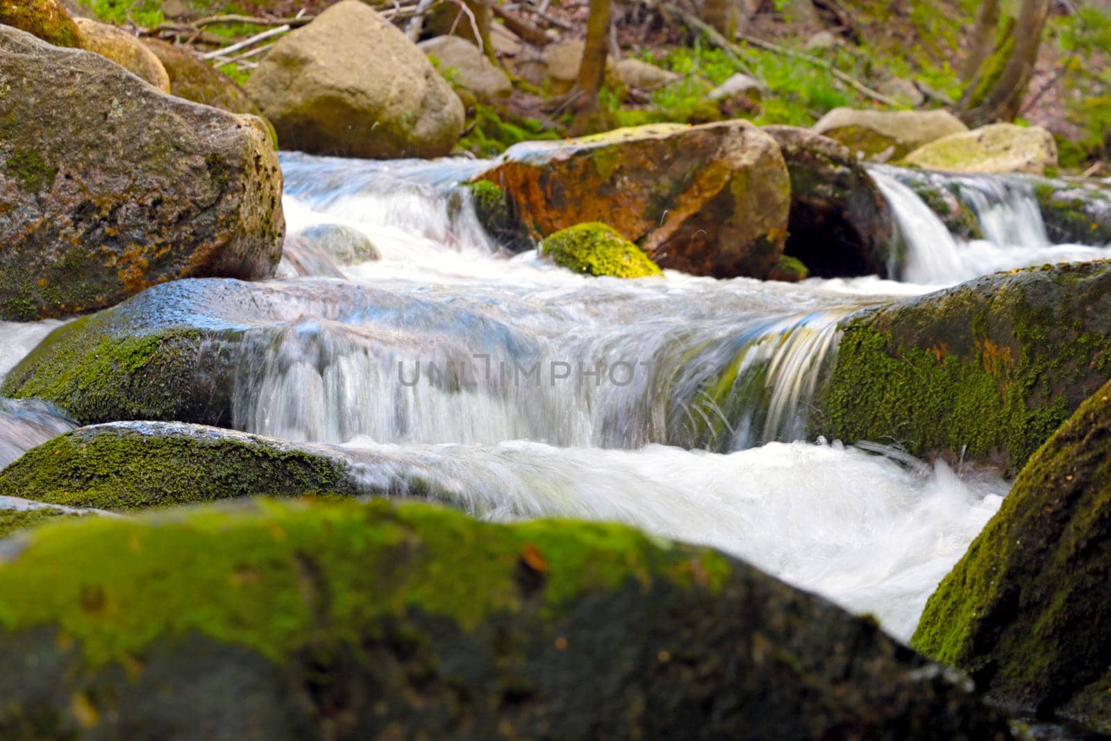 A small picturesque river flows through stones with moss in the forest. by kip02kas