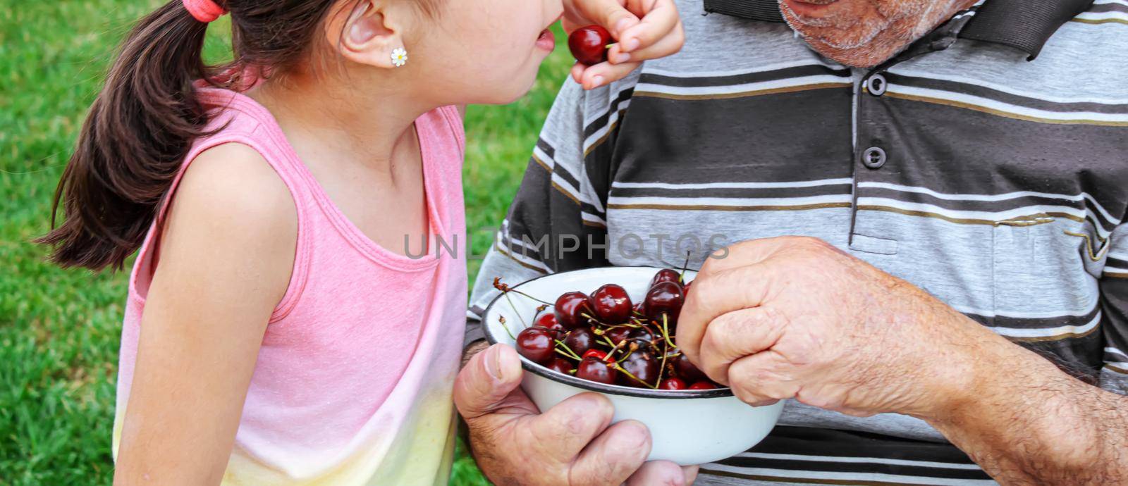 grandparents feed the child with cherries.selective focus. by mila1784