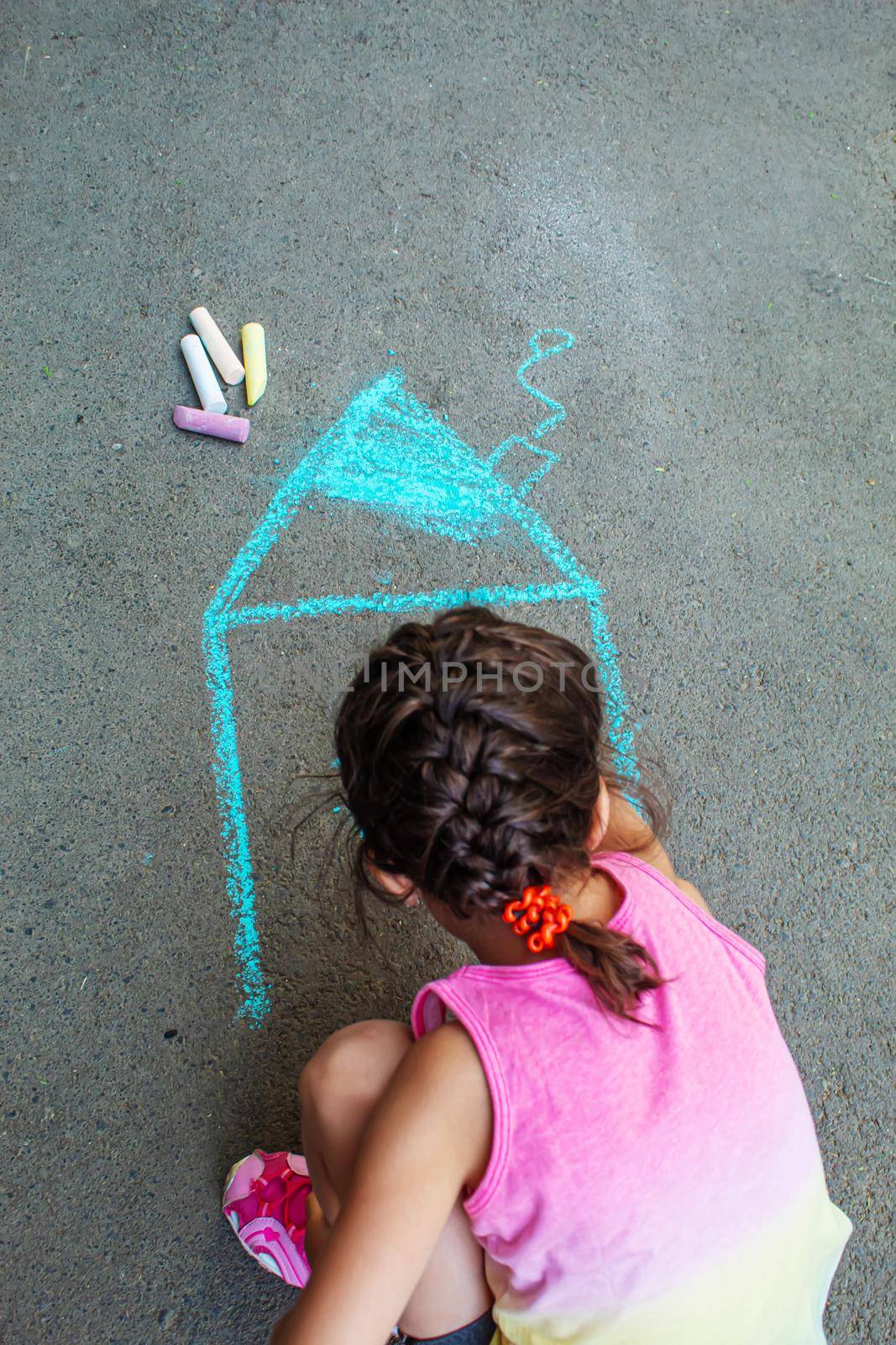 The child draws the house with chalk on the asphalt. Selective focus. draw.