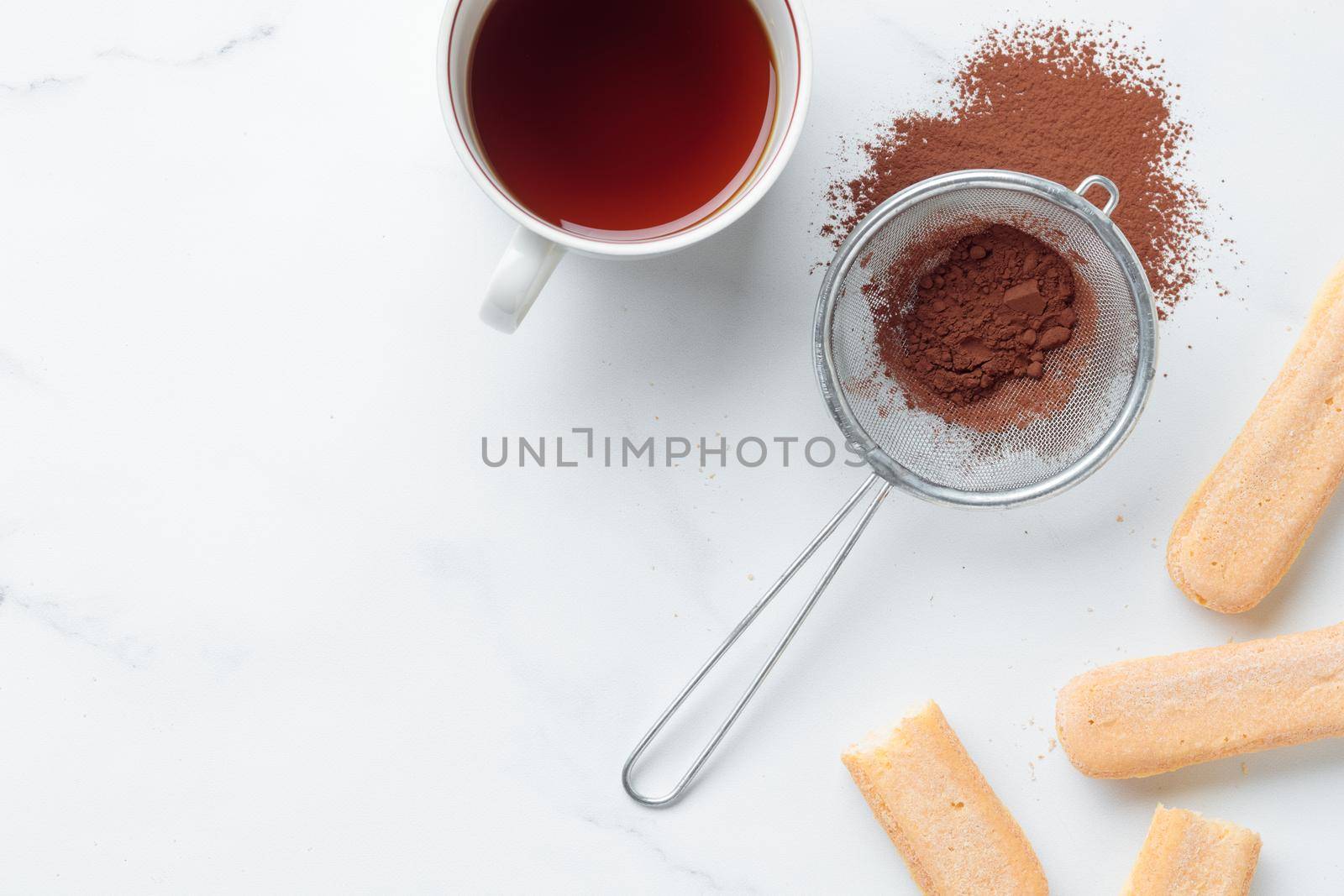 Tiramisu ingredients: Italian cookie savoiardi, coffee and cocoa powder top view on a white background