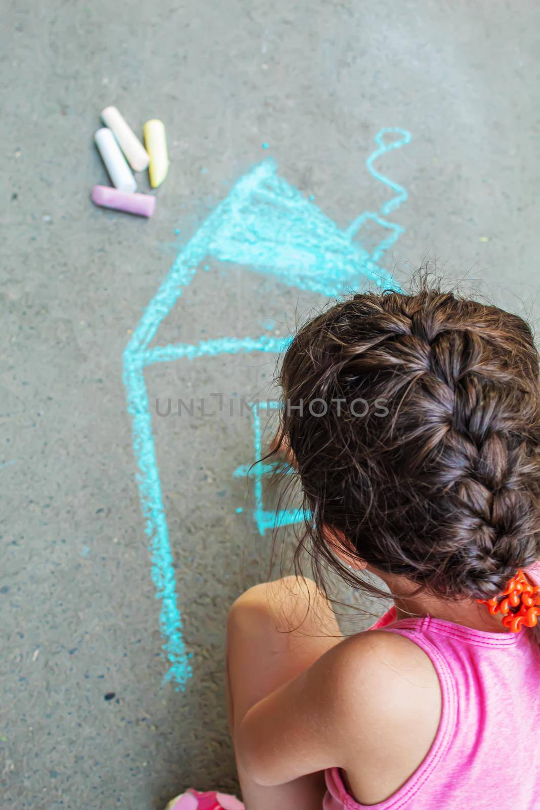 The child draws the house with chalk on the asphalt. Selective focus. draw.