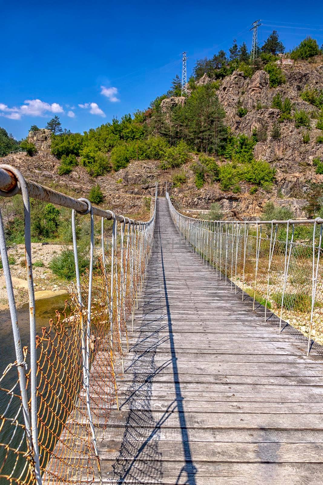 Wooden rope suspension bridge for walk crossing river in the mountain by EdVal