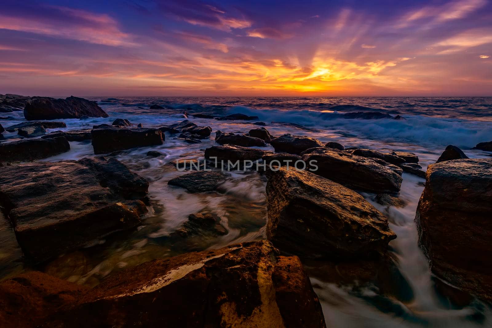 The stunning seascape with the colorful sky and last rays at the rocky coastline of the Black Sea