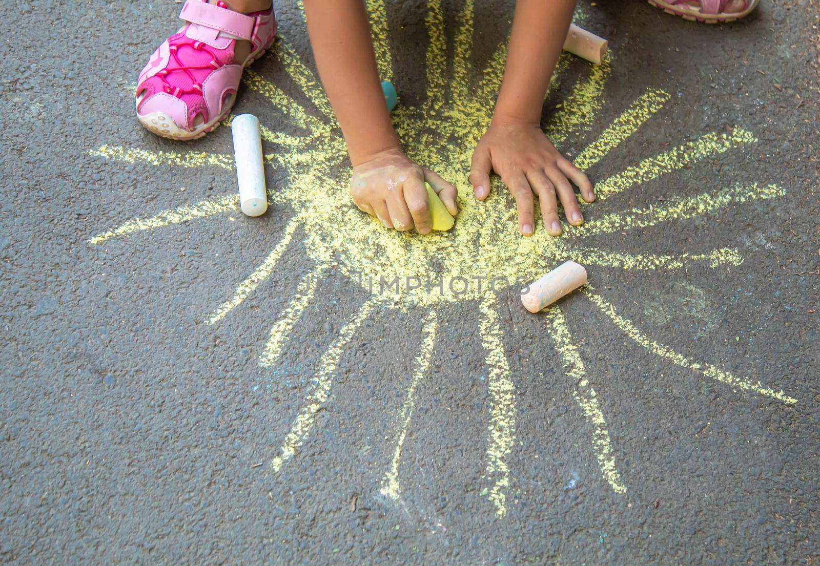 child draws with chalk on the pavement. Selective focus.