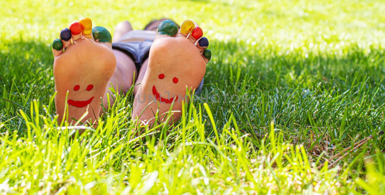 Children's feet with a pattern of paints smile on the green grass. Selective focus. nature.