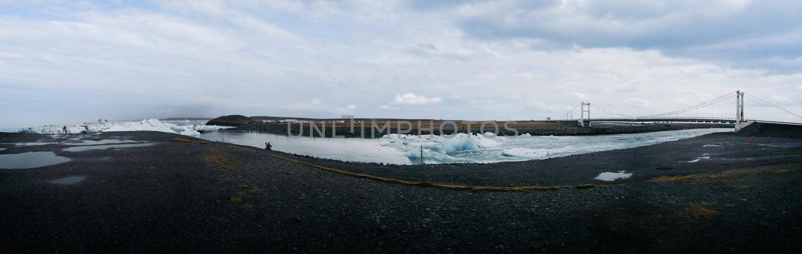 Jokulsarlon lagoon icebergs canal to the ocean wide panorama with suspension bridge