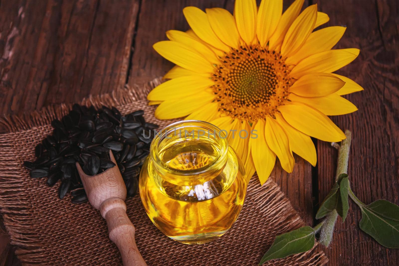Sunflower seeds and oil bottle on old wooden background. Selective focus. by mila1784