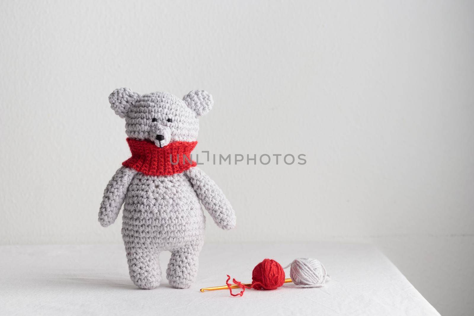 Crochet knitting cute teddy bear with a red scarf