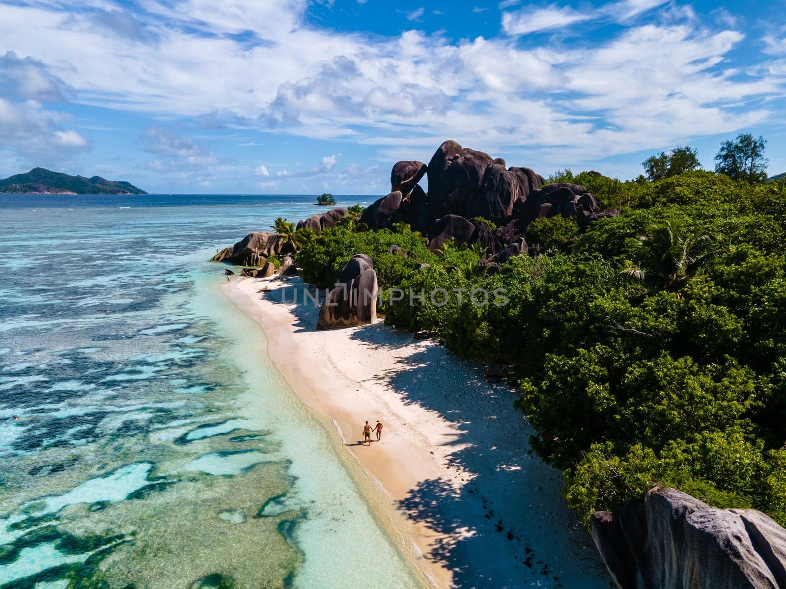 Anse Source d'Argent beach, La Digue Island, Seyshelles, Drone aerial view of La Digue Seychelles bird eye view, couple men and woman walking at the beach during sunset at a luxury vacation by fokkebok