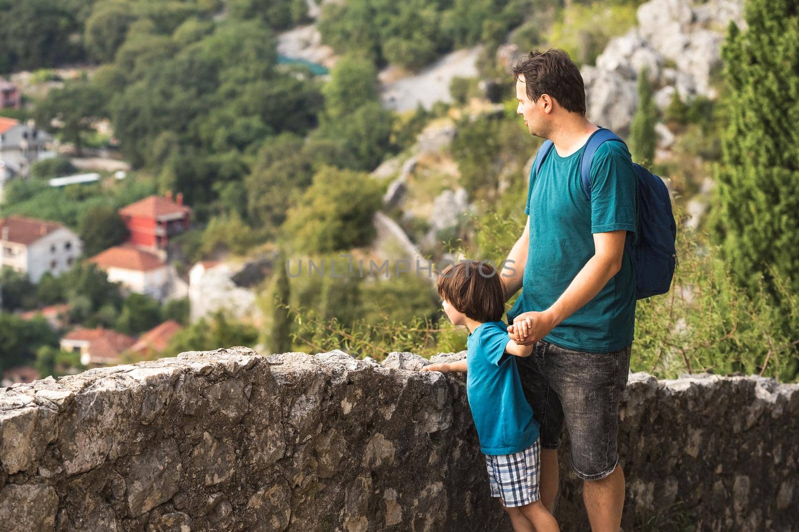 Father and his little son looking at the panoramic view of the old Mediterranean city from the Viewpoint. Kotor Bay in Montenegro