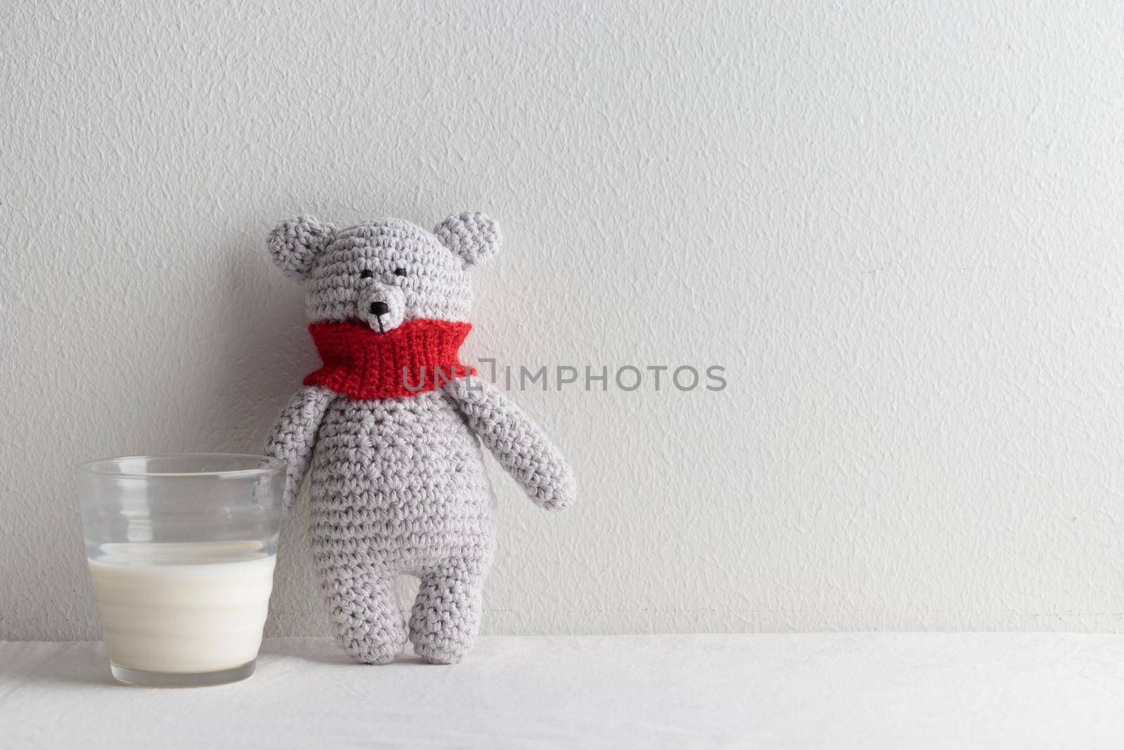 rochet knitting cute teddy bear with a glass of milk on a white table