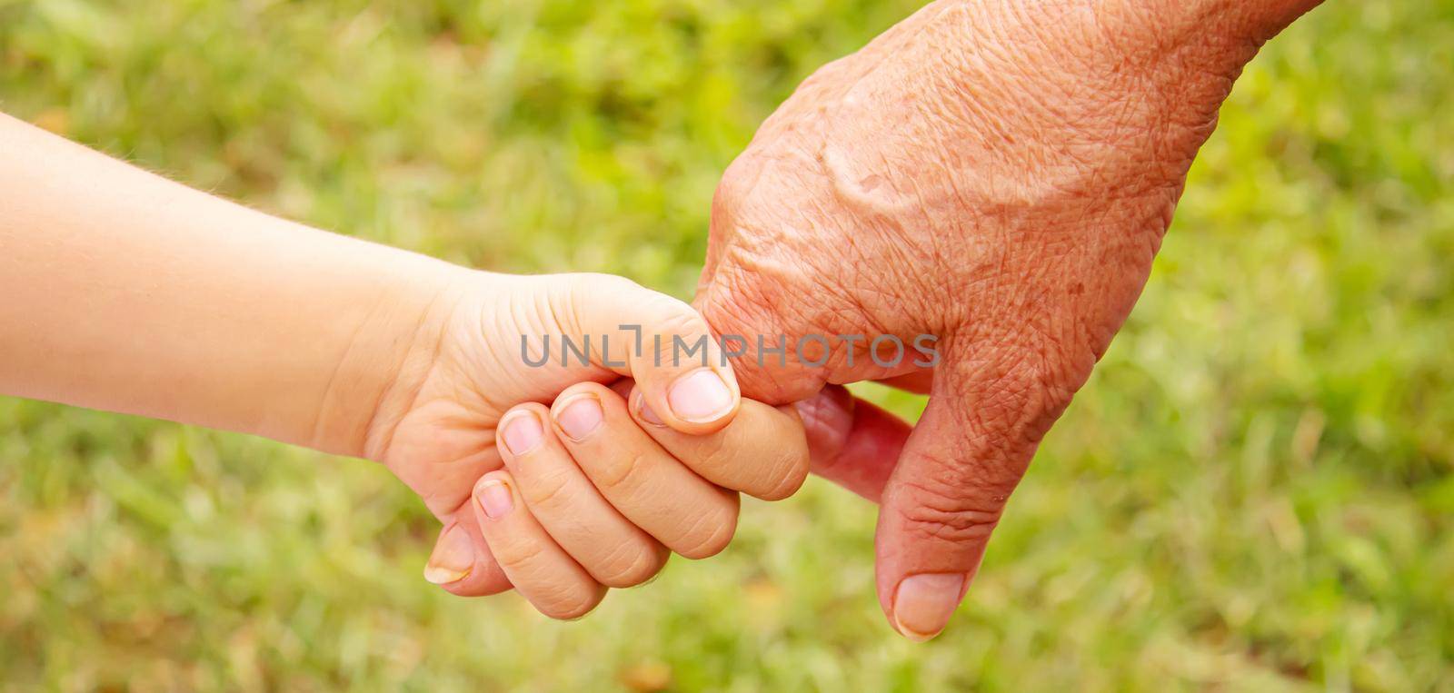 old man holding child's hands. selective focus by mila1784