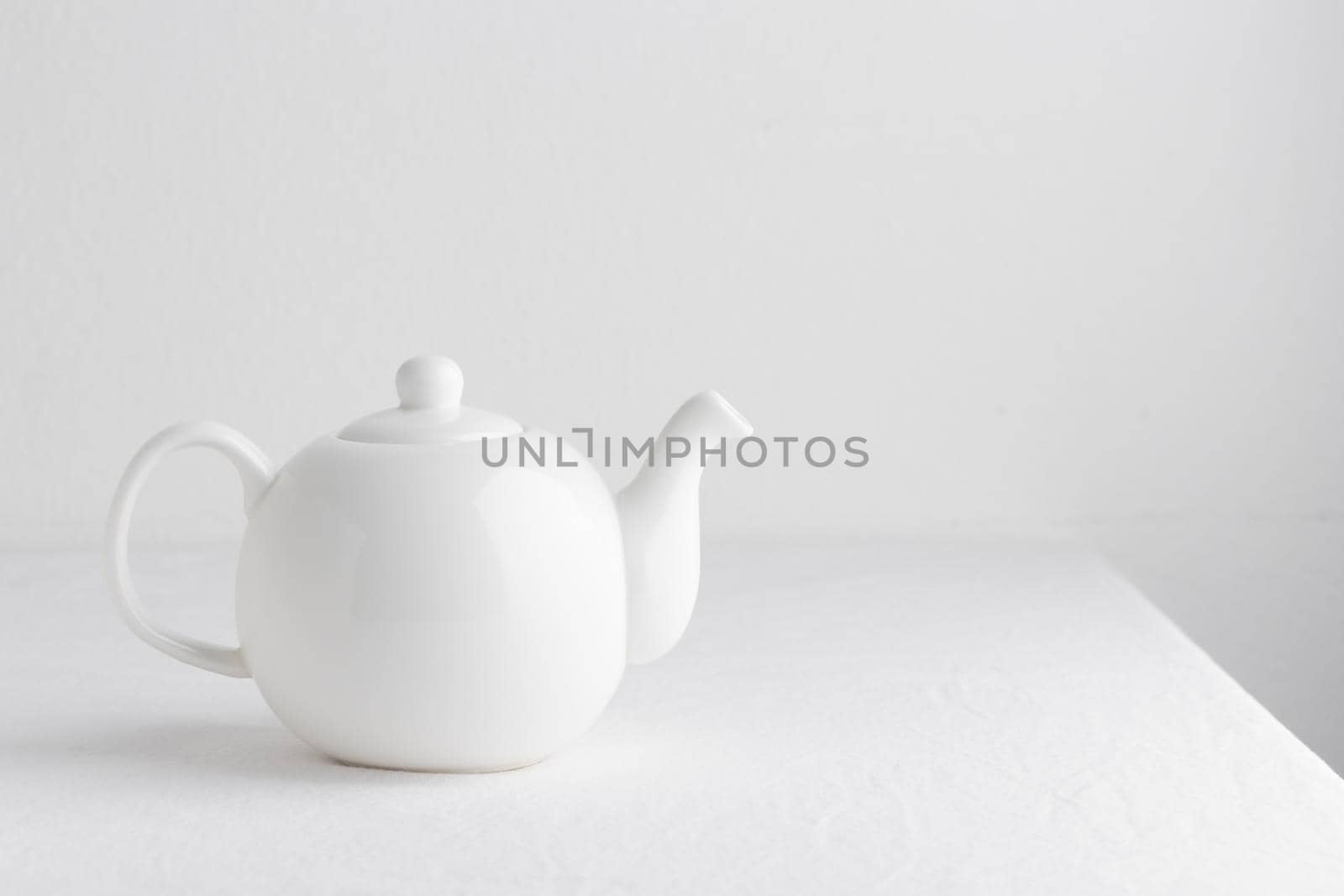 White teapot on a table on a white background