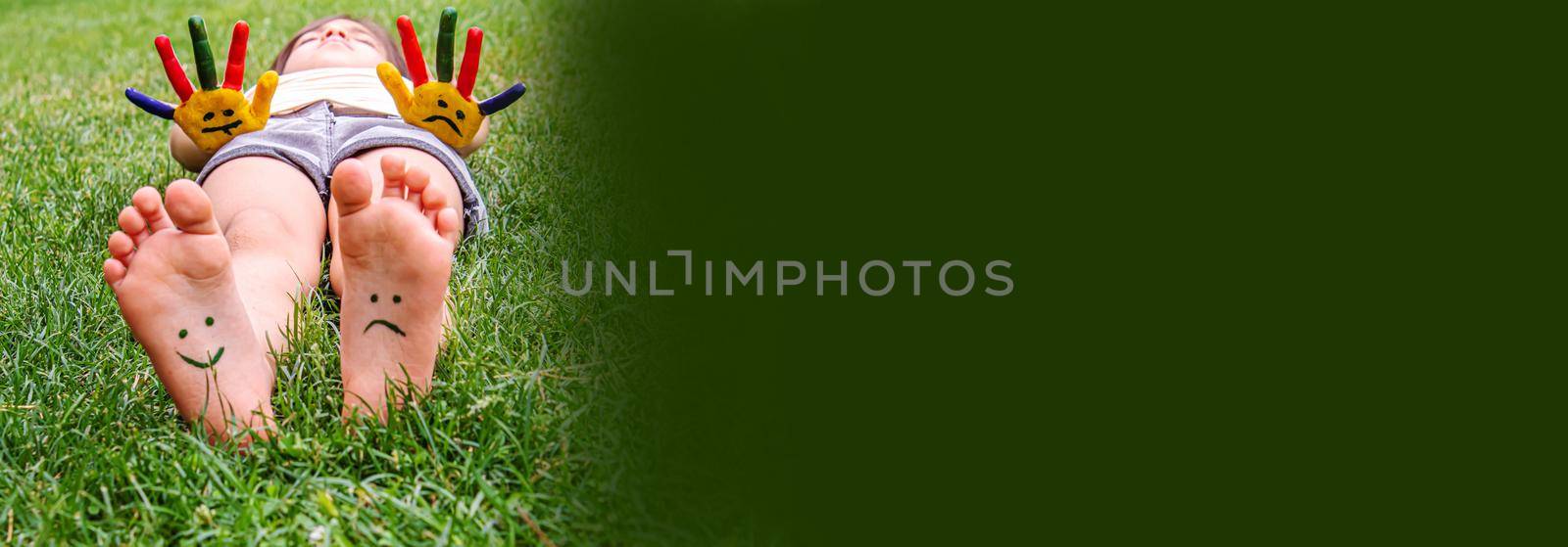 Baby feet with paint pattern are smiling and sad on the green grass. Selective focus. nature.