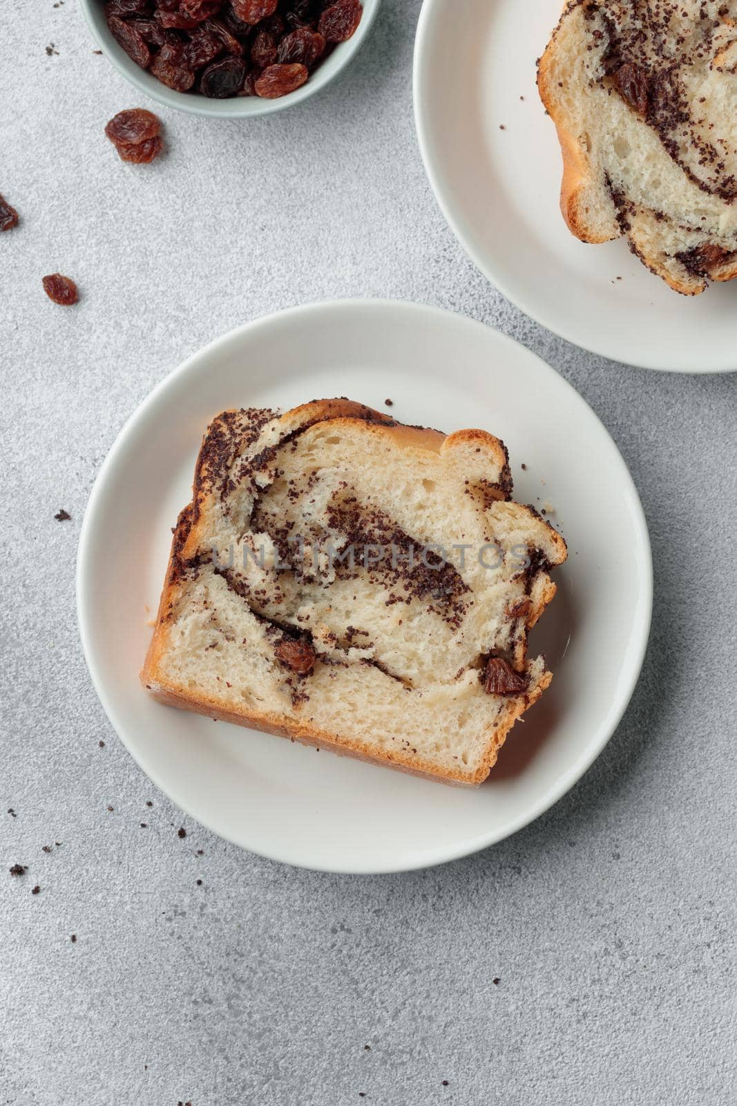 Piece of swirl homemade bread with poppy seeds on a white table