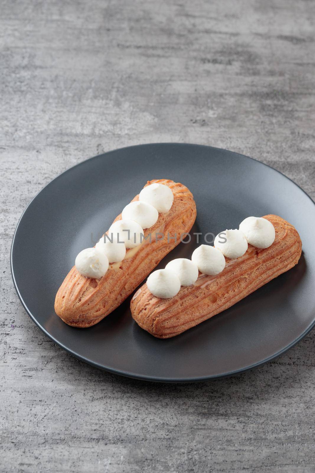 Traditional French dessert sweet eclairs on a gray background