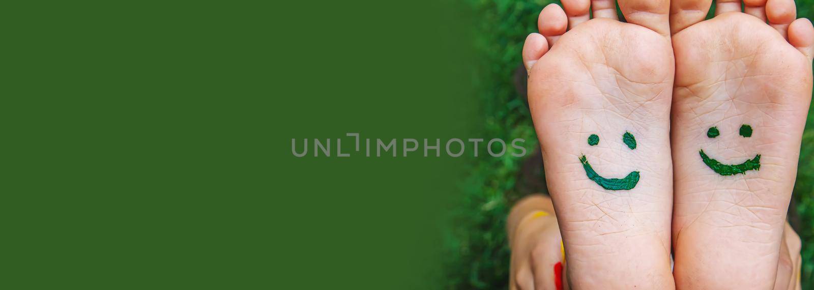 Children's feet with a pattern of paints smile on the green grass. Selective focus. by mila1784