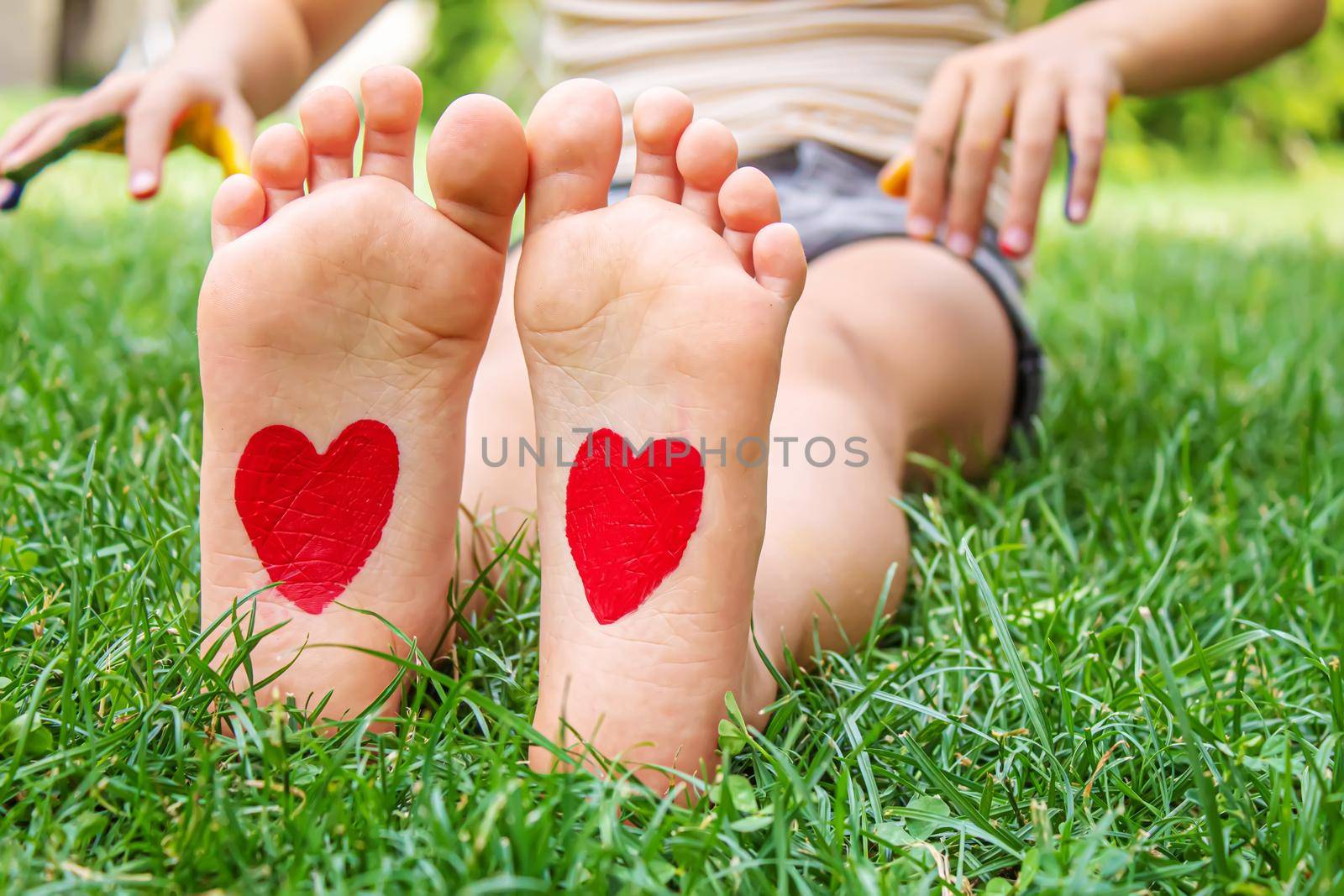 Baby legs with a pattern of a heart on the green grass. Selective focus. nature.