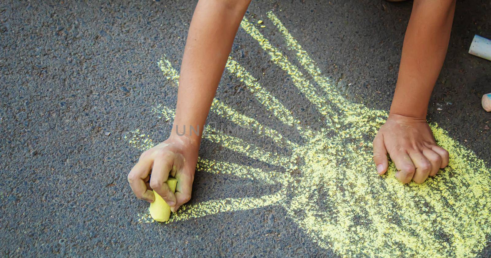 child draws with chalk on the pavement. Selective focus.arts by mila1784