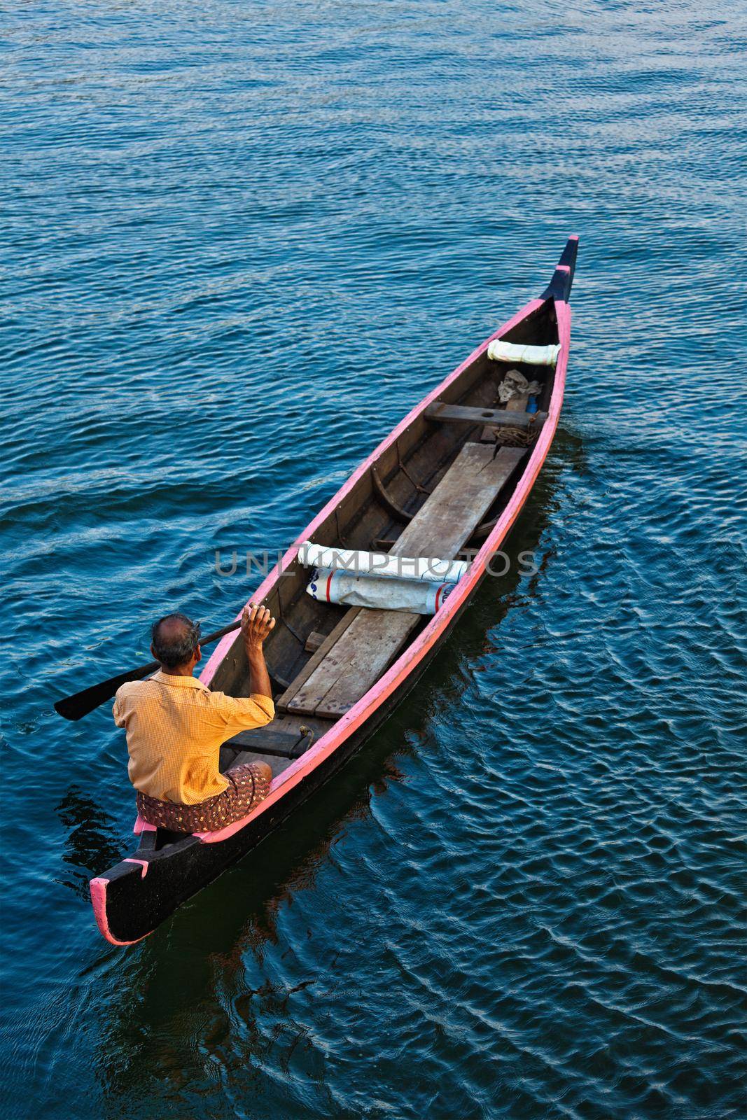 KERALA, INDIA - MAY 5, 2010: Indian man in small canoe boat in backwaters. Kerala backwaters are both major tourist attraction and integral part of local people life in Kerala