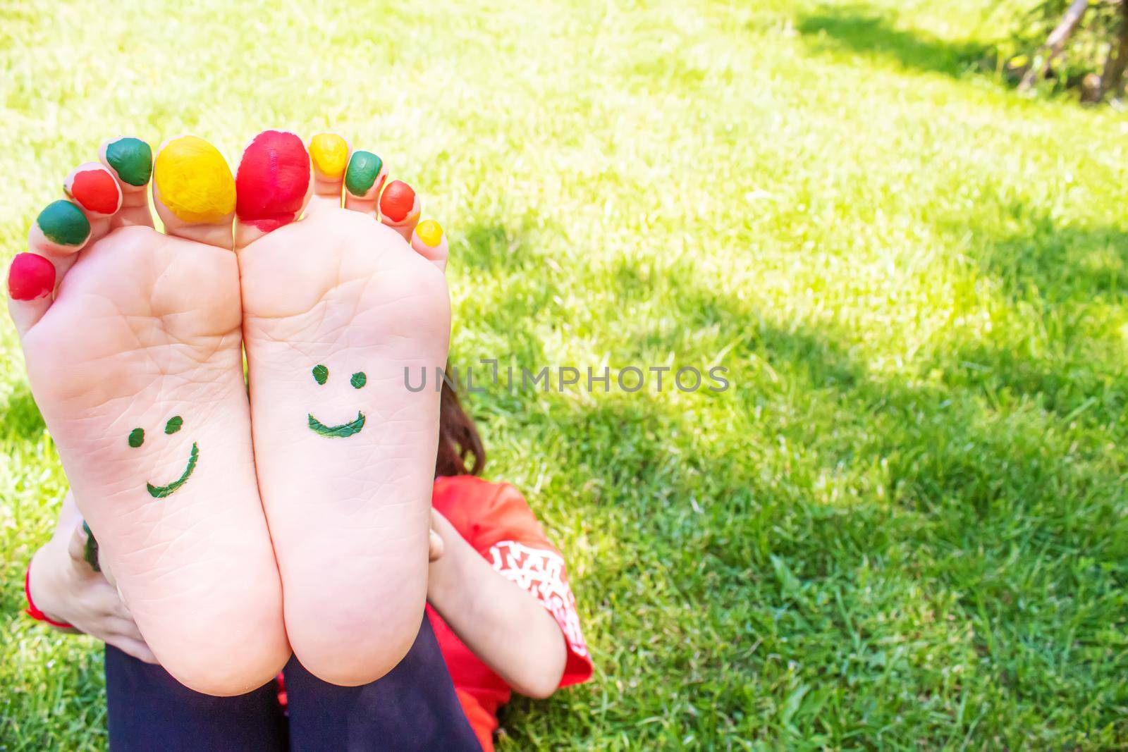 Children's feet with a pattern of paints smile on the green grass. Selective focus. nature.